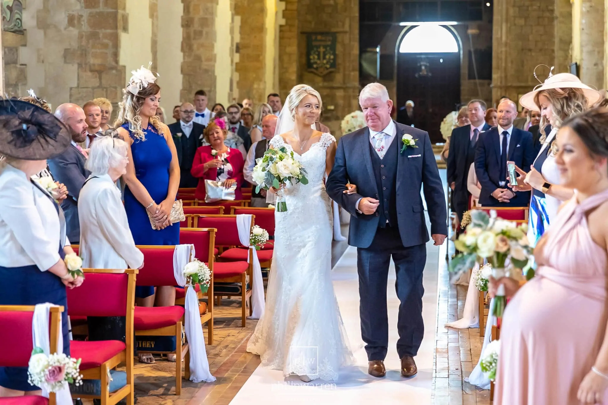 bride and her dad walking down the aisle at st marys church in chepstwo smiling with all the guests standing around them